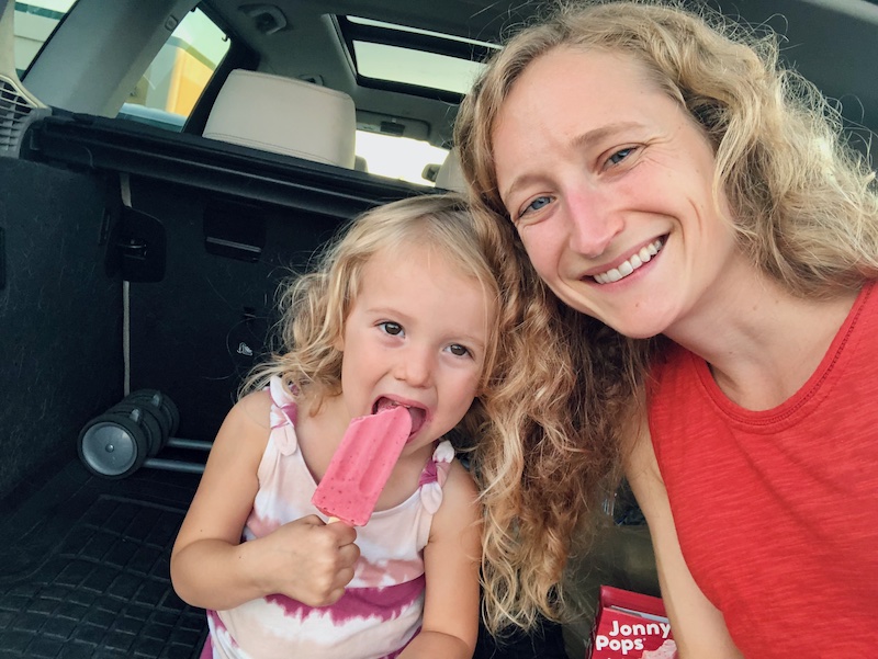 Mom and toddler eating Johnny Pops in the back of car