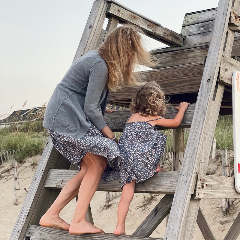 Mom and daughter climbing lifeguard chair at beach in Kill Devil Hills, NC