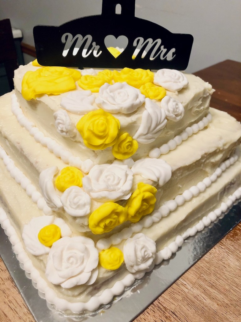 Three layer wedding cake with white and yellow roses