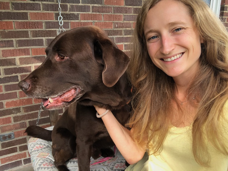 Girl sitting with chocolate lab on porch swing