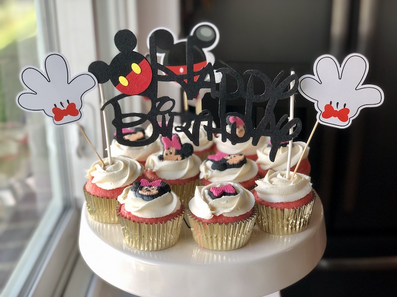 Mickey Mouse birthday cupcakes with Minnie Mouse decorations and happy birthday cake topper