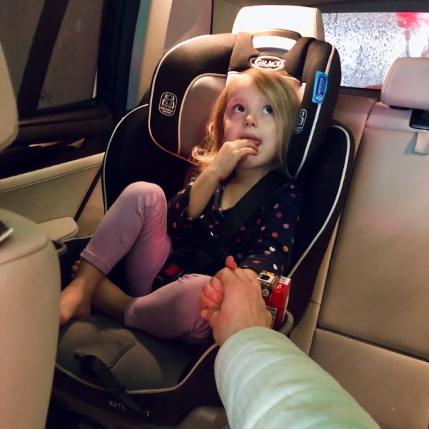 Toddler in carseat at carwash holding mom's hand