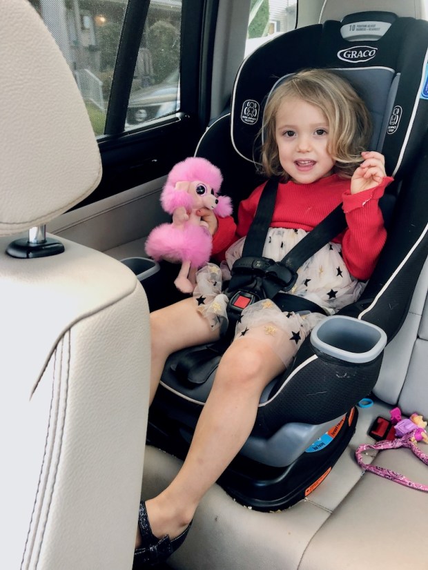 Toddler girl wearing formal dress and holding a Beanie Boo in carseat