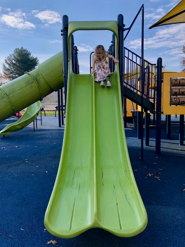 Toddler girl going down a slide at a park in Pittsburgh, PA