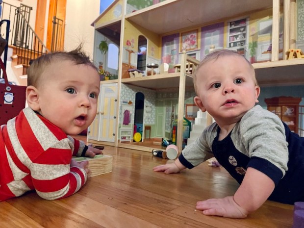 Babies laying on floor by dollhouse 