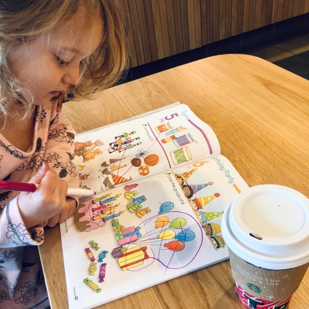 Toddler girl doing preschool worksheets at Starbucks