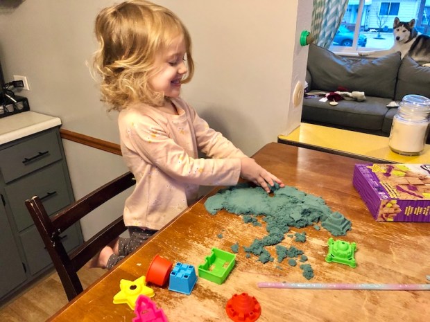 Toddler playing with kinetic sand set