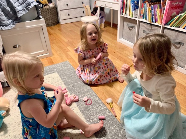 Three toddlers playing with fake makeup 