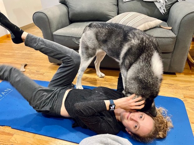 Girl trying to do yoga with husky