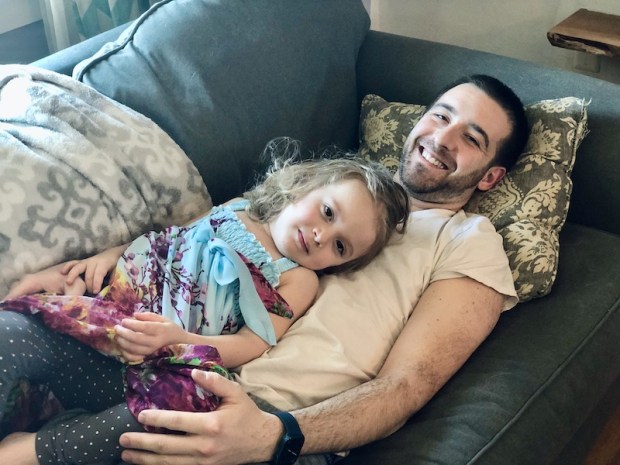 Dad and toddler laying on couch together