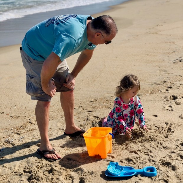 Grandpa and granddaughter playing on beach in Kill Devil Hills, NC in the Outer Banks