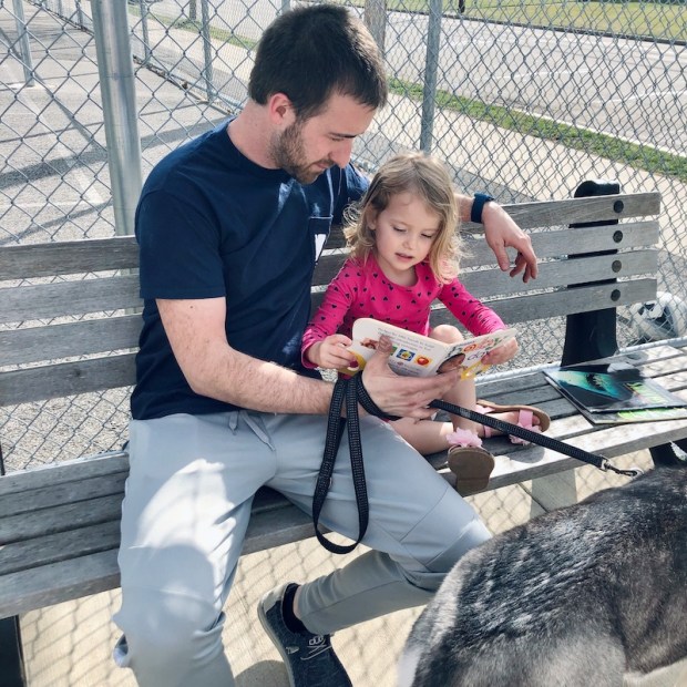 Father and daughter reading on park bench