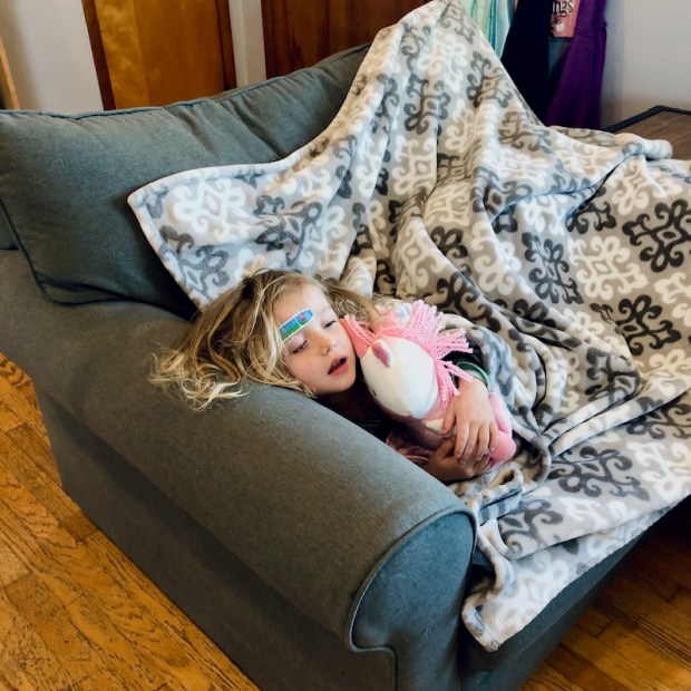 Toddler laying on couch with stuffed unicorn and blanket