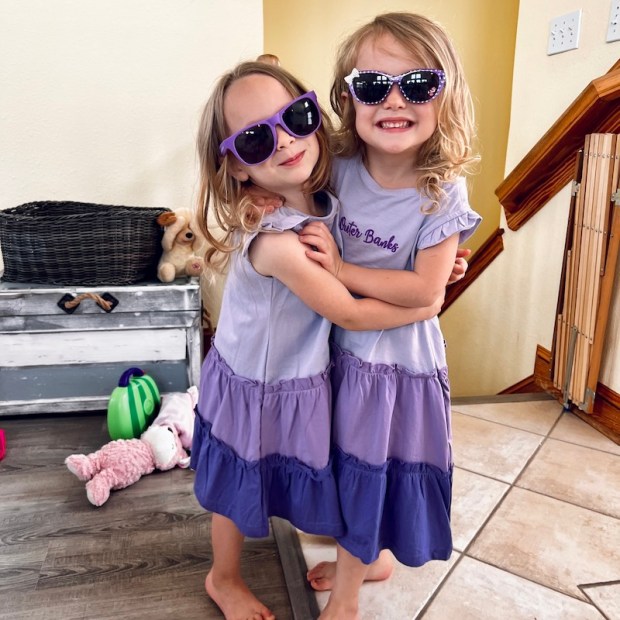 Toddler girls wearing matching purple dresses