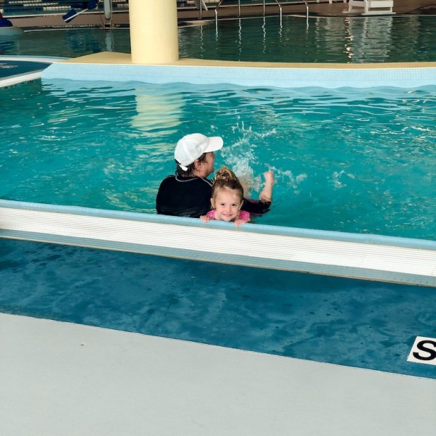 Toddler girl taking swim lessons in pool