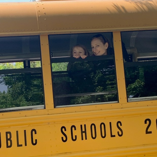 Mom and daughter on school bus looking out window