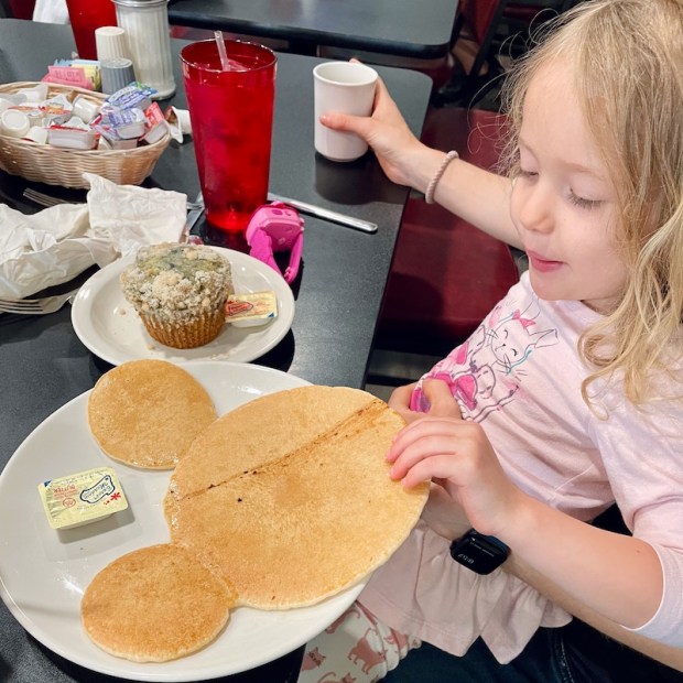 Girl with Mickey Mouse pancake at diner