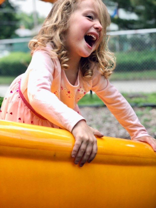Girl on yellow slide smiling