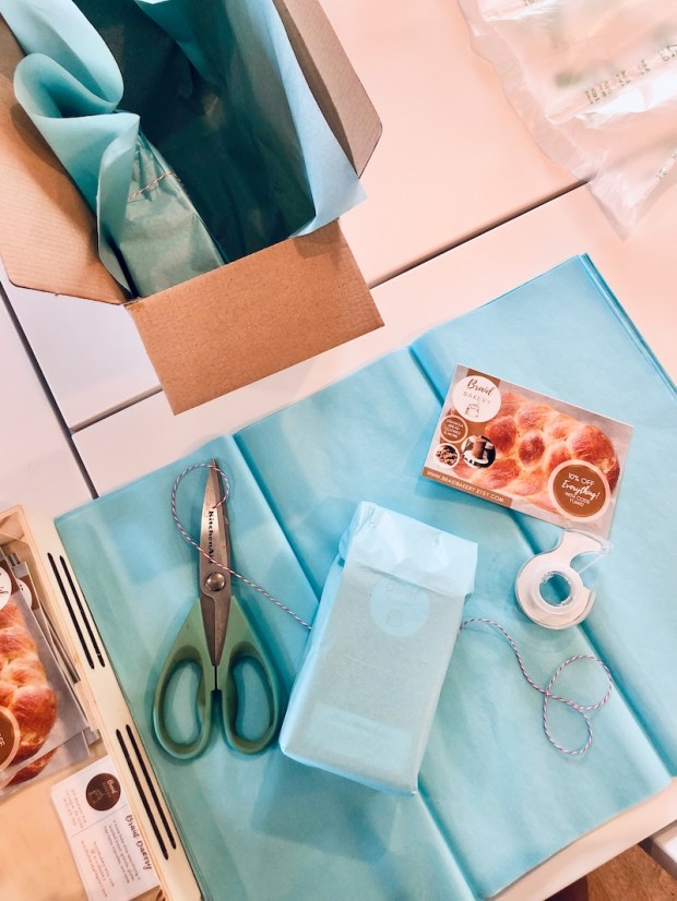 Etsy shop packing up orders with blue gift tissue