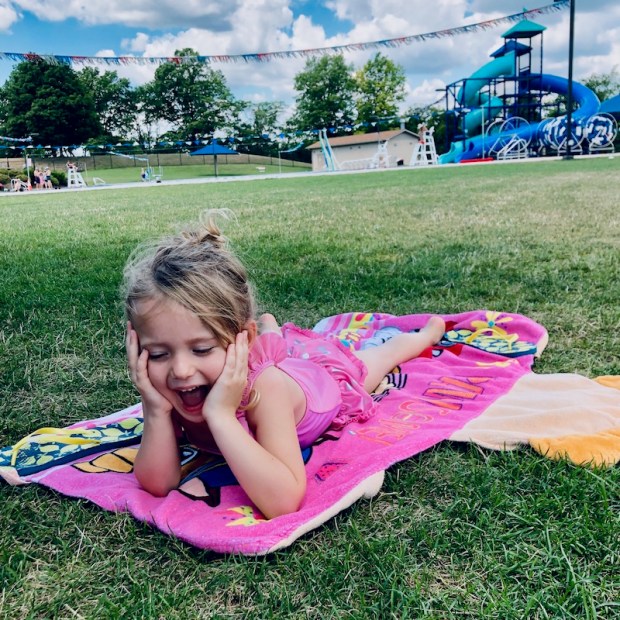 Girl laying on towel by pool