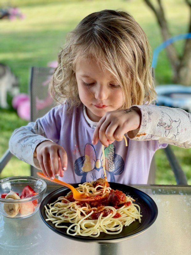 Young girl eating spaghetti and meatballs