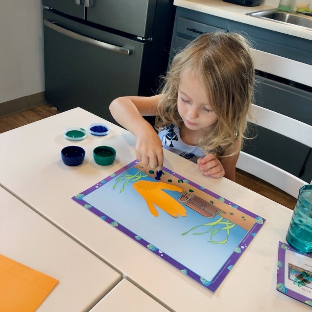 Young girl finger painting with Abeka homeschool cirriculum