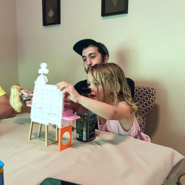 Guy playing Barbies with child