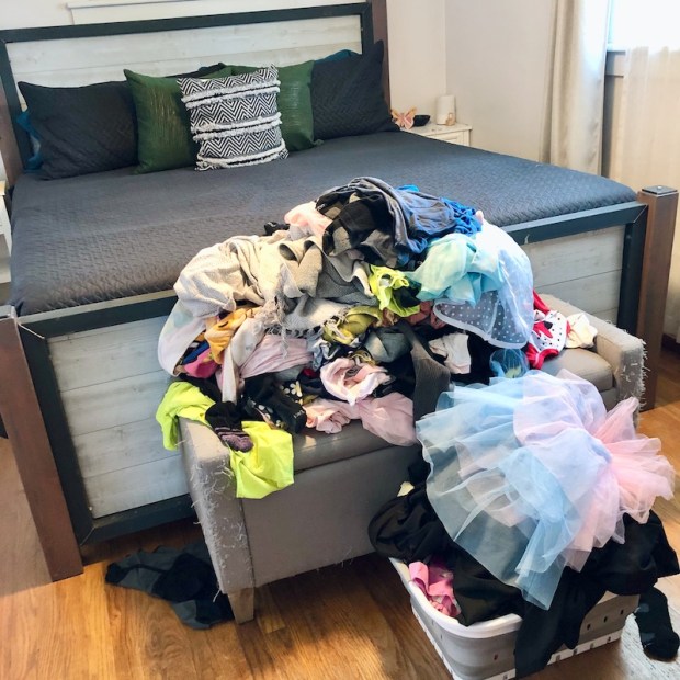 Clean laundry piled up near bed