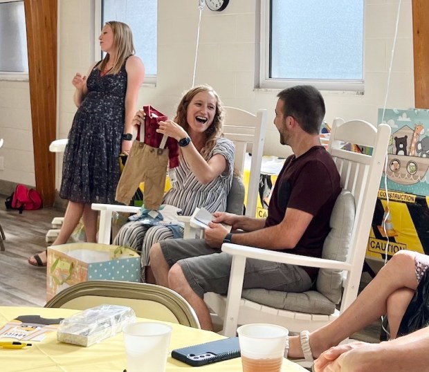 Husband and wife opening baby boy gifts at baby shower