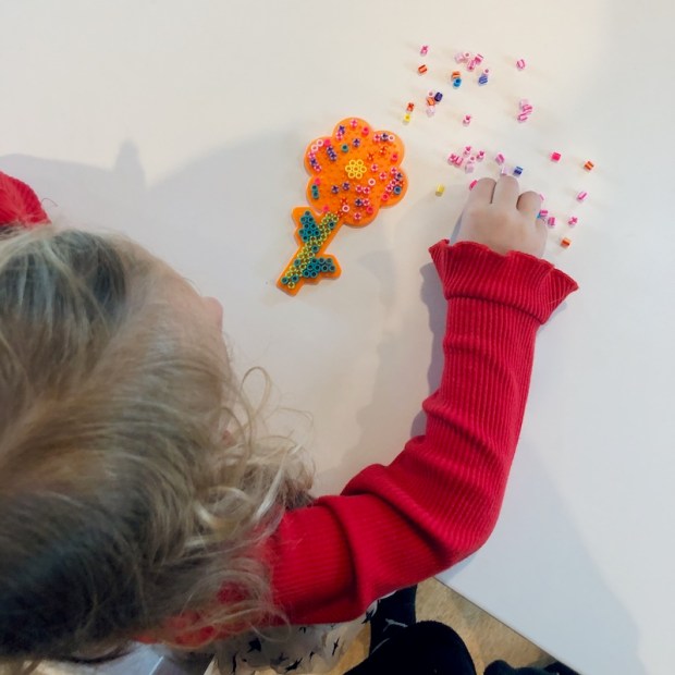 Girl sitting at table doing perler beads