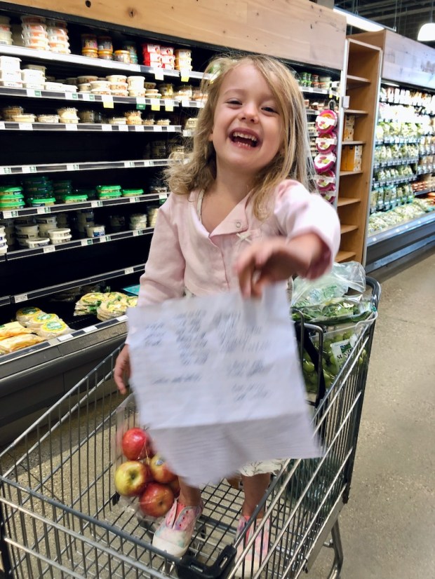 Young girl holding grocery list in cart at Whole Foods