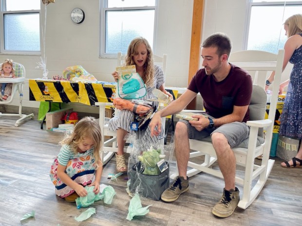 Family opening up baby shower gifts at baby boy sprinkle