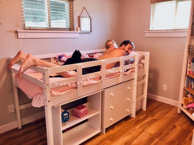 Girl and dad laying on white loft bed with cat