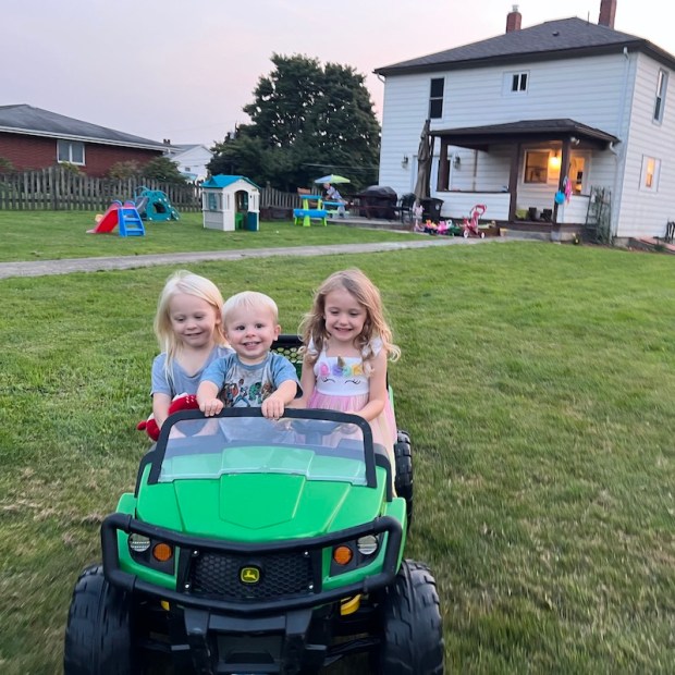 Three kids riding in John Deere powerwheel