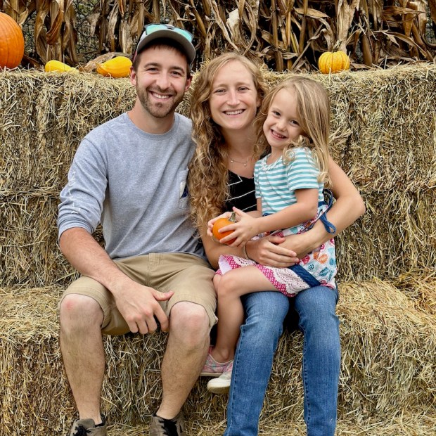 Mom and dad with daughter sitting on hay at a fall festival