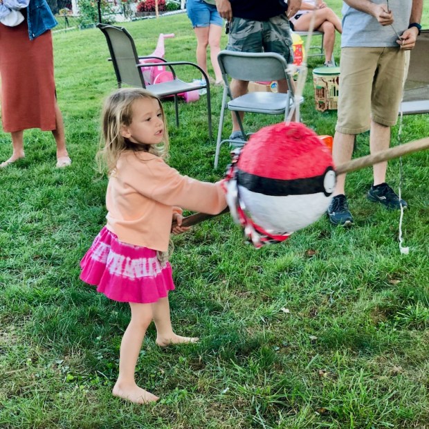 Girl hitting Pokemon poke ball pinata