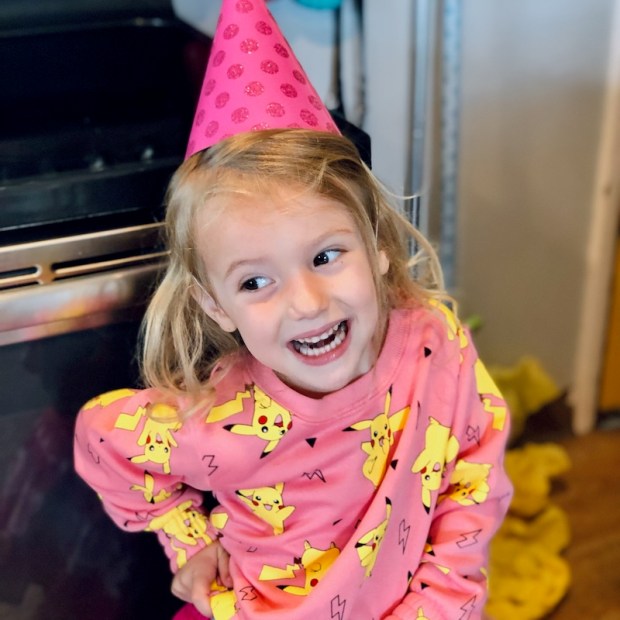 Girl wearing Pokemon sweatshirt and pink party hat