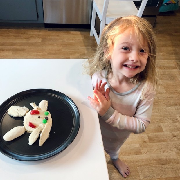 Young girl standing by plate with bunny rabbit pancake