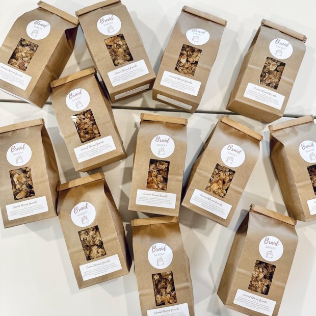 Bags of coconut almond granola from Braid Bakery laying on white table
