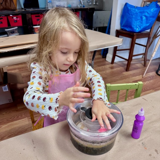 Girl using salad spinner to make spin art with paint