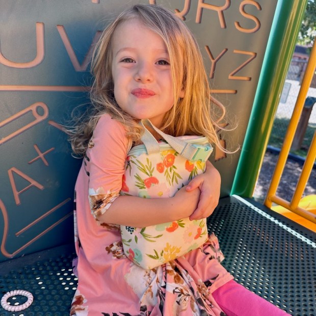 Girl holding lunch box at park