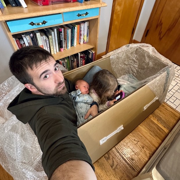 Dad holding newborn in a box with four year old
