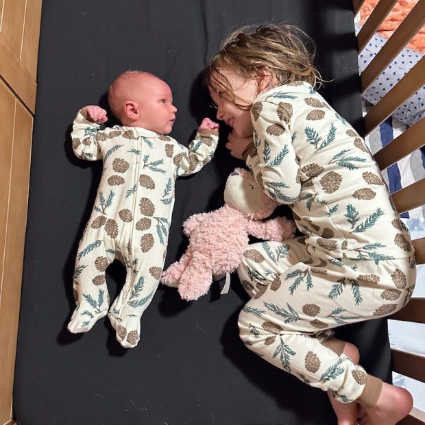 Newborn baby and sister in matching pajamas