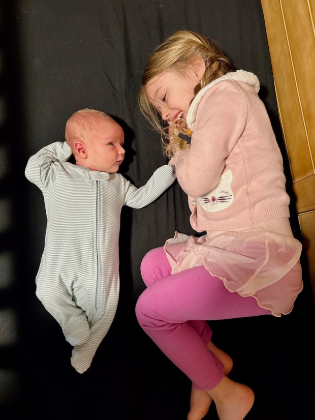 Big sister laying with newborn brother in crib