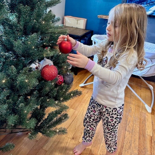 Four year old hanging ornaments on Christmas tree