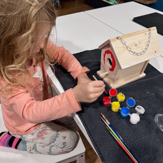 Preschooler painting a wooden birdhouse