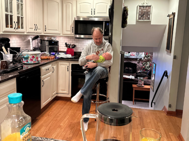 Grandpa holding baby grandson in kitchen