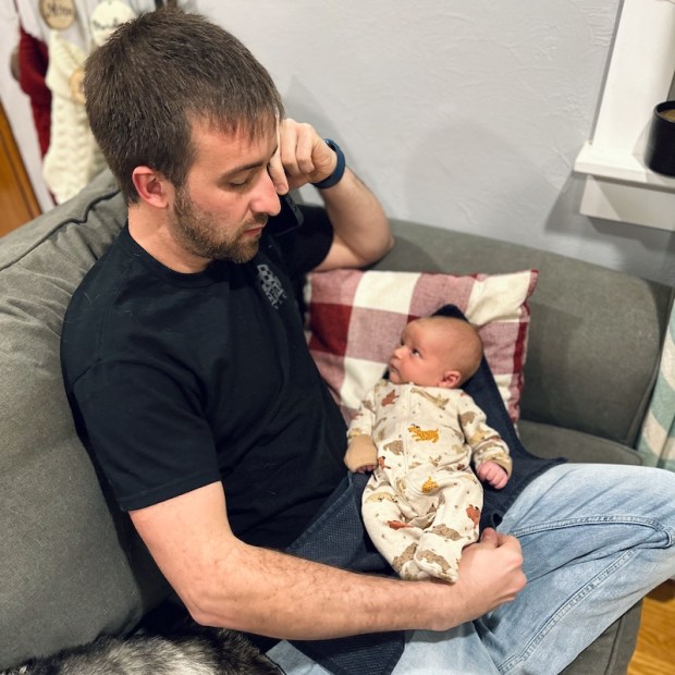Dad sitting on the couch with newborn baby looking at him