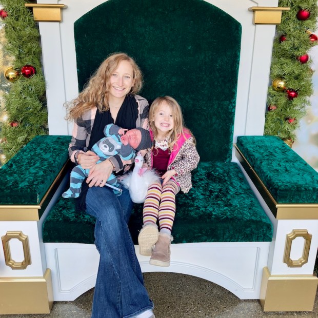 Mom sitting on Christmas chair at the Aviary with baby and preschooler