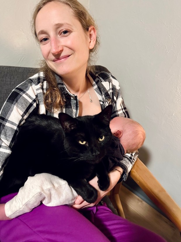 Girl nursing baby boy with cat on her
